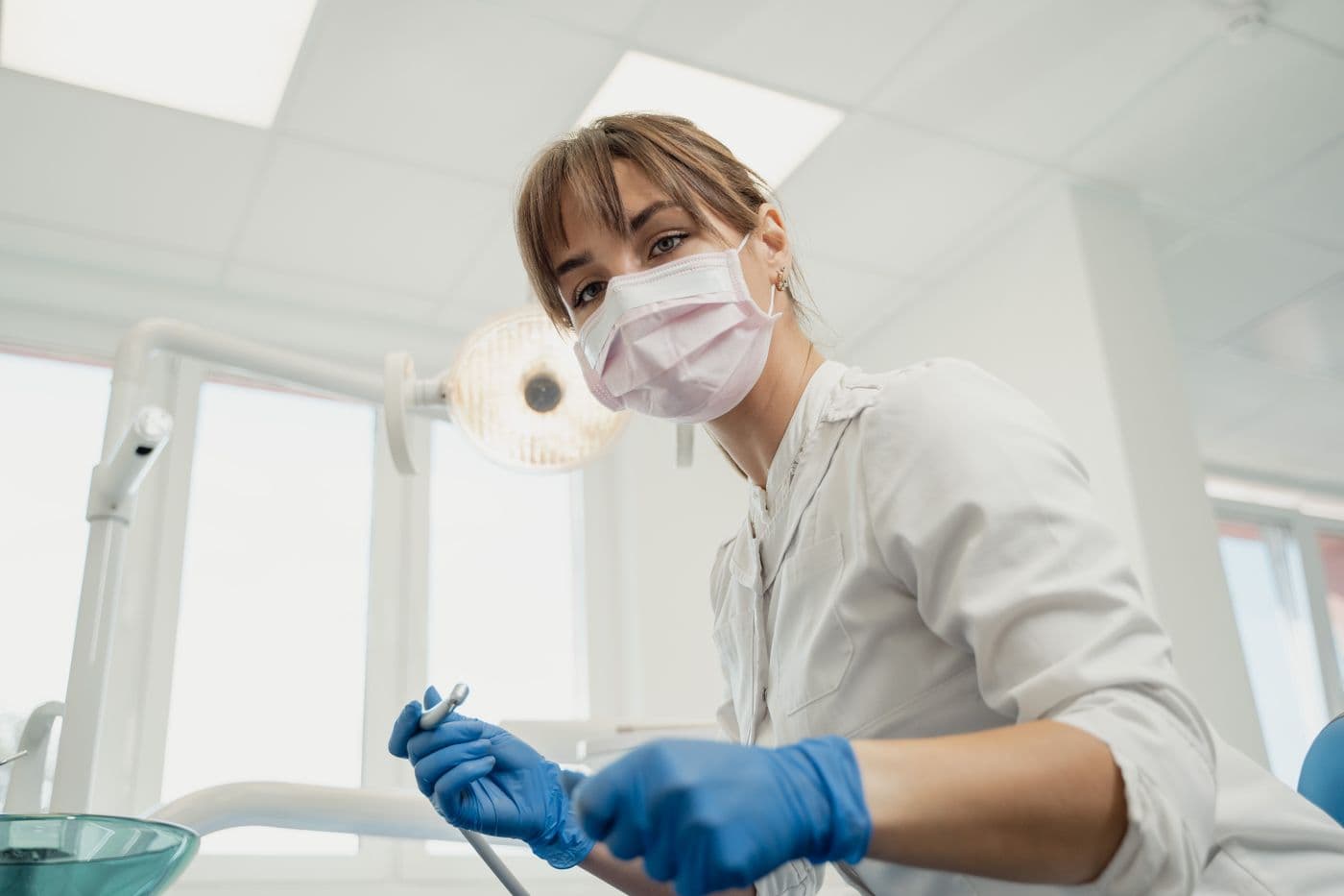 A dentist in clinic attire preparing to treat a patient