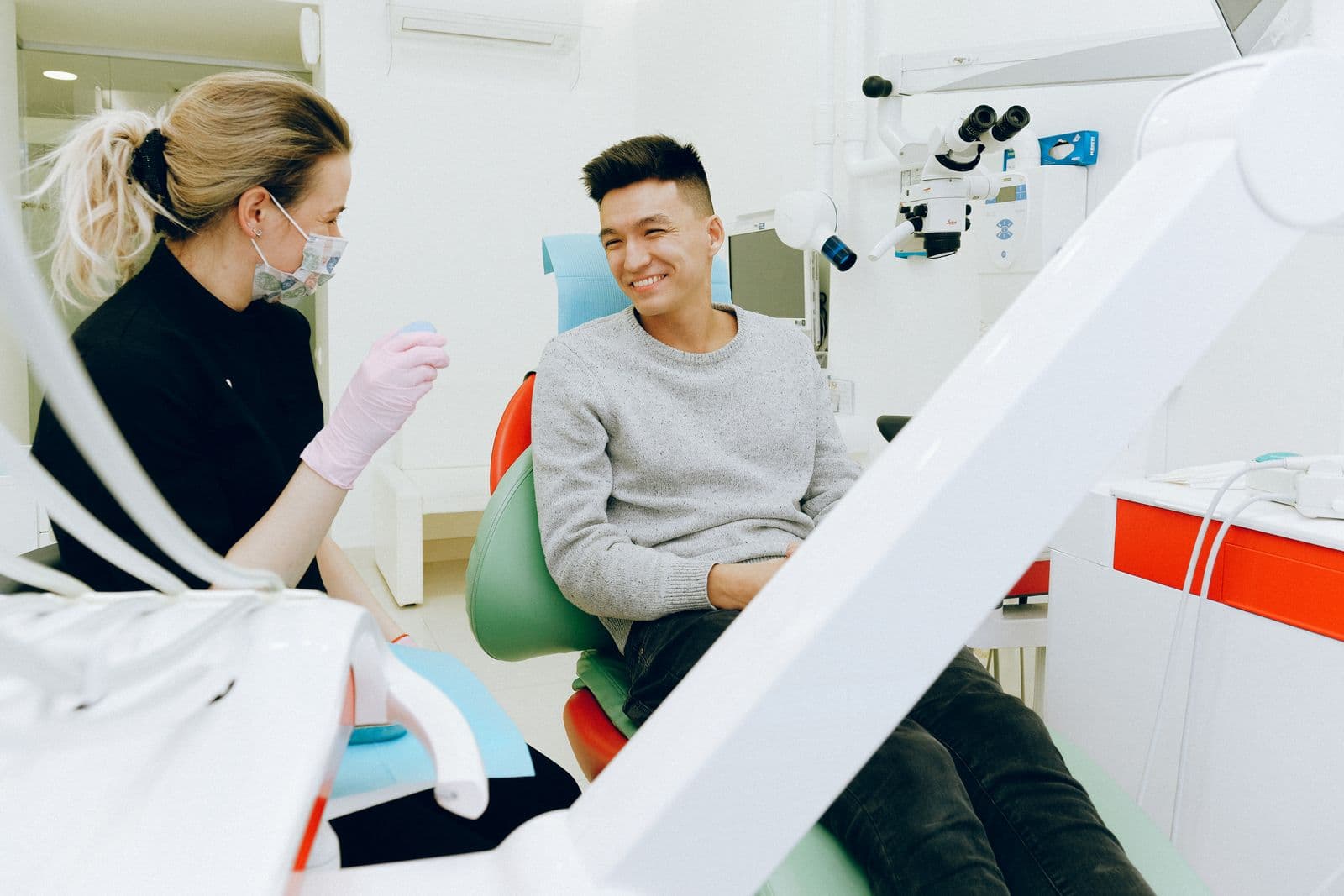 A dentist speaking with a smiling patient in the dental chair